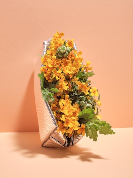 Sac cosmétique couleur argent avec des fleurs jaune vif et des feuilles vertes sur fond orange pastel. Ensemble cadeau luxueux.