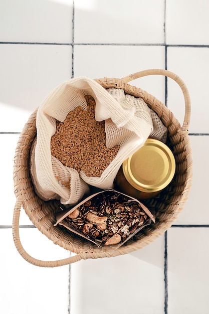 sac en coton réutilisable avec graines de lin, bocal en verre et granola maison dans un sac en papier le tout dans un panier