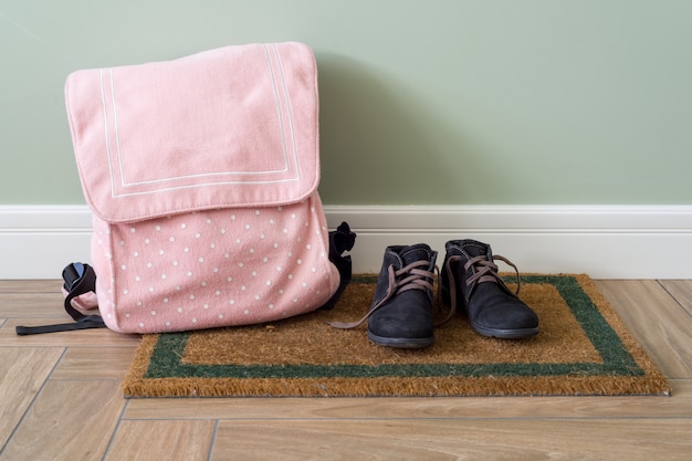 Sac à dos d'école et des bottes sur le sol