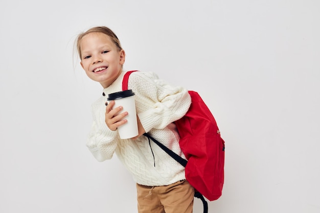 Sac à dos d'école de petite fille avec un chapeau sur la tête fond isolé