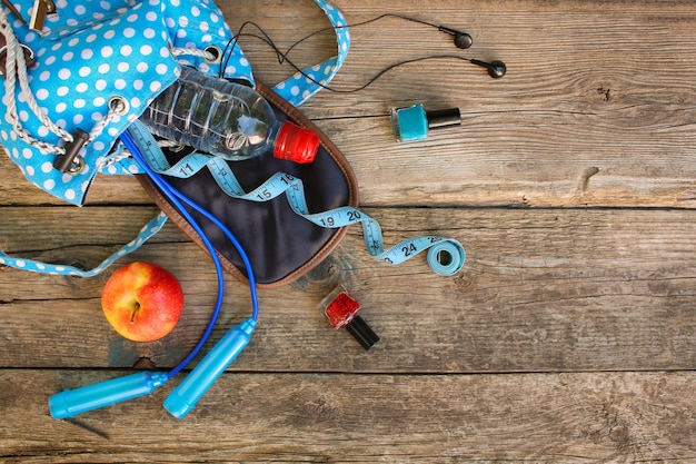 Sac à dos femme avec équipement sportif, cosmétique, ruban à mesurer, eau. Vue de dessus