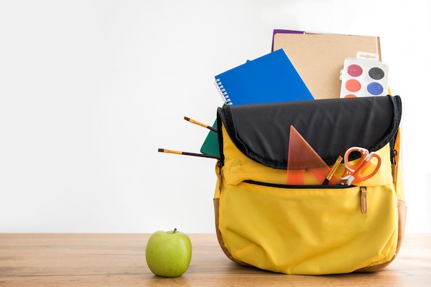 Sac à dos jaune avec fournitures scolaires et pomme