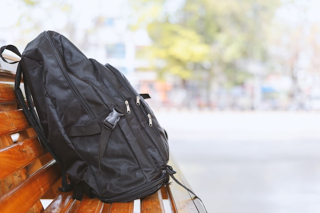 Sac à dos noir sur une table en bois dans les gares routières avec flou artistique et lumière en arrière-plan