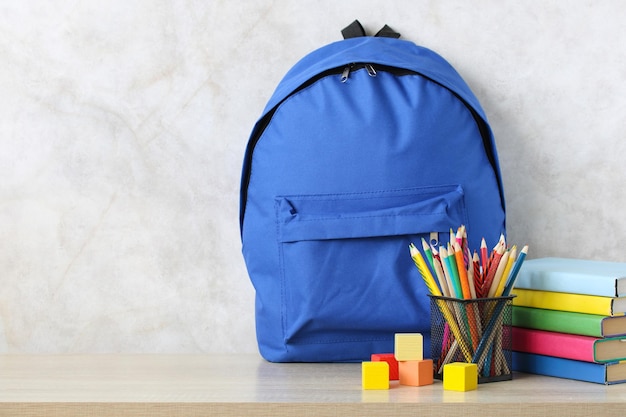 Un sac à dos scolaire bleu manuels scolaires et crayons sur le bureau