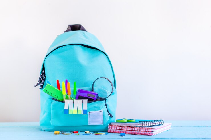 Photo sac à dos scolaire turquoise avec papeterie sur table.