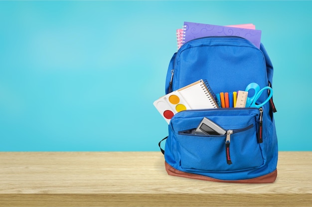 Sac à dos violet avec fournitures scolaires isolé sur blanc