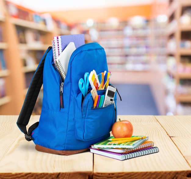 Sac à dos violet avec des fournitures scolaires isolées sur blanc