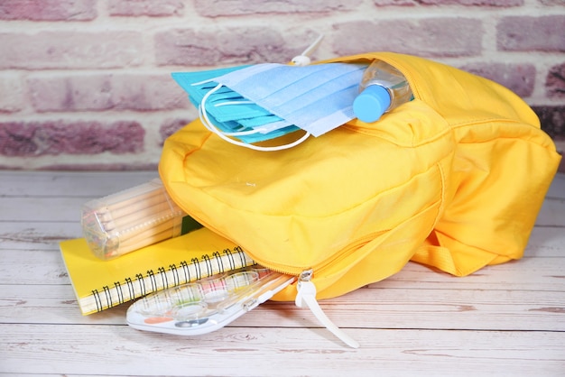 Photo sac d'école étudiant avec désinfectant, un masque facial.