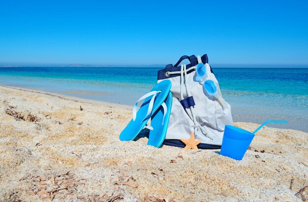 Sac d'été et boisson sur un rivage blanc