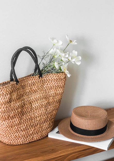 Un sac d'été en paille d'osier un chapeau et un magazine sur un banc en bois