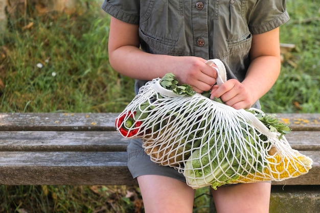 Sac en fil de coton avec des légumes entre les mains d'une petite fille