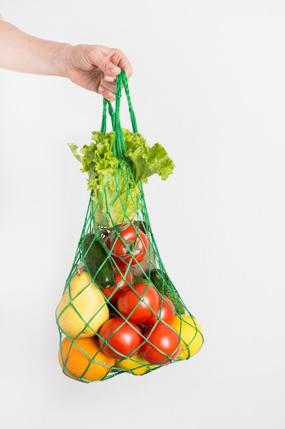 Sac en filet avec des légumes dans la main de la femme.