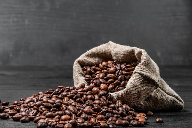 Sac avec des grains de café dispersés isolés sur fond noir