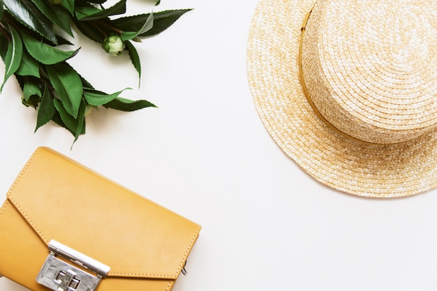 Sac jaune, plante et chapeau de paille sur fond beige. Vue de dessus, surface