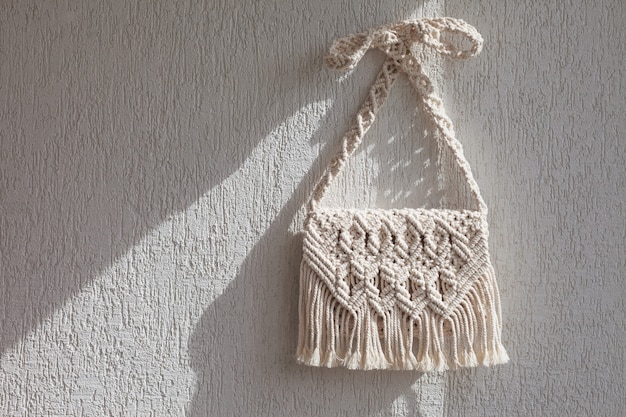 Sac en macramé fait main sur le mur lumineux.