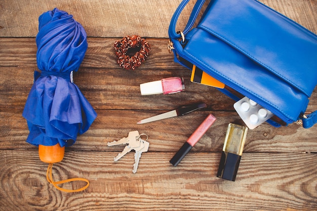 Sac à main bleu, parapluie et accessoires pour femmes. Choses du sac à main de dame ouverte. Vue de dessus. Image tonique.