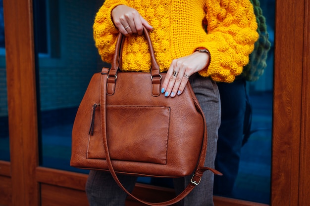 Sac à main. Femme tenant un sac élégant et portant un pull jaune.