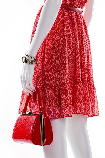 Sac à main et montre sur mannequin. Mannequin femme avec sac à main élégant. Robe ondulée et accessoires élégants. Tenue d'été rouge pour dame.