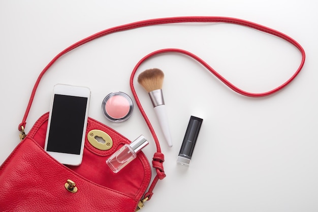 Sac de mode femme rouge avec cosmétique, parfum et smartphone