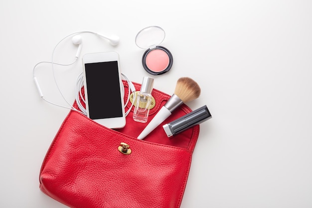 Sac de mode femme rouge avec cosmétique et smartphone