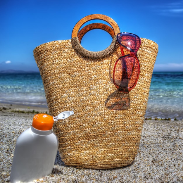 Sac en paille et lotion solaire au bord de la mer Traité pour un effet de mappage des tons hdr