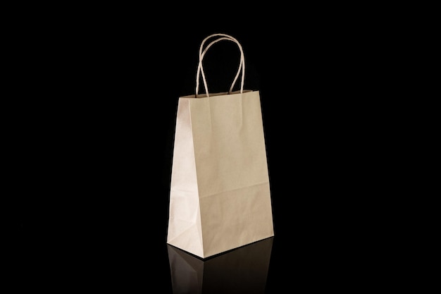 Sac en papier artisanal recyclable pour les achats, les cadeaux et la nourriture à emporter sur fond noir Plus respectueux de l'environnement que les sacs en plastique à usage unique