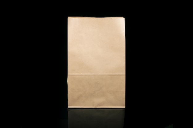 Sac en papier artisanal recyclable pour les achats, les cadeaux et la nourriture à emporter sur fond noir Plus respectueux de l'environnement que les sacs en plastique à usage unique