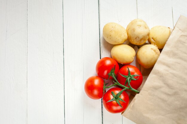 Sac en papier beige sur un blanc en bois, légumes du magasin