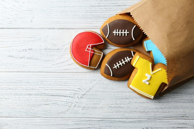 Photo sac en papier avec des biscuits créatifs décorés dans un style football sur fond en bois
