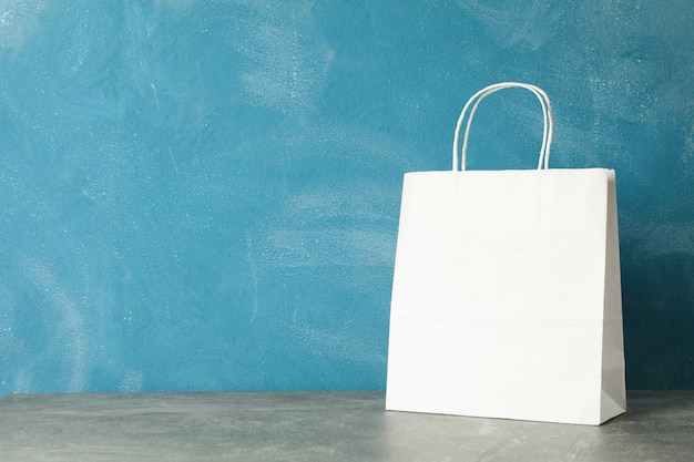 Sac en papier blanc sur table grise contre bleu