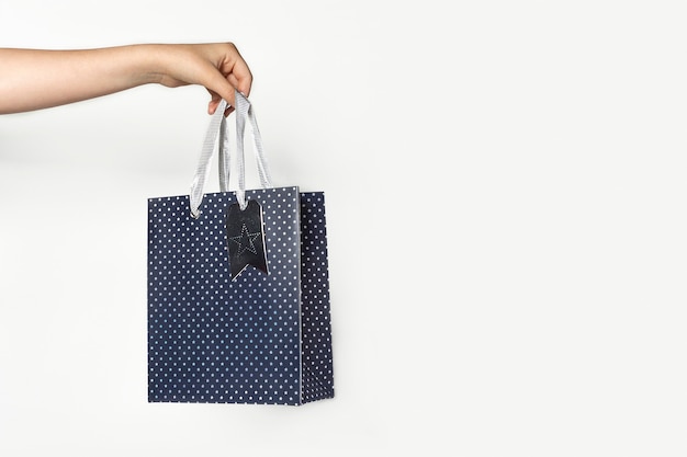 Sac en papier cadeau en main de femme sur fond blanc