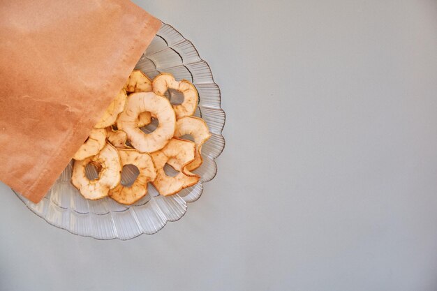 Sac en papier avec des croustilles de pommes séchées en tranches des collations saines à la mode sur la plaque Vue de dessus Concept de nutrition appropriée