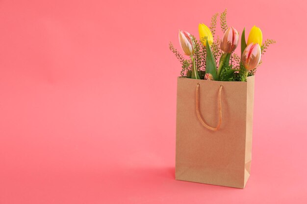 Sac en papier avec des fleurs sur fond rose