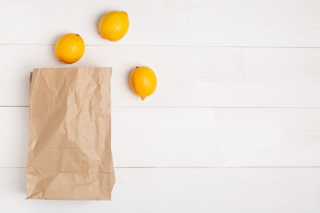 Sac en papier sur un fond blanc en bois avec un espace vide pour le texte. Lay plat, vue de dessus.