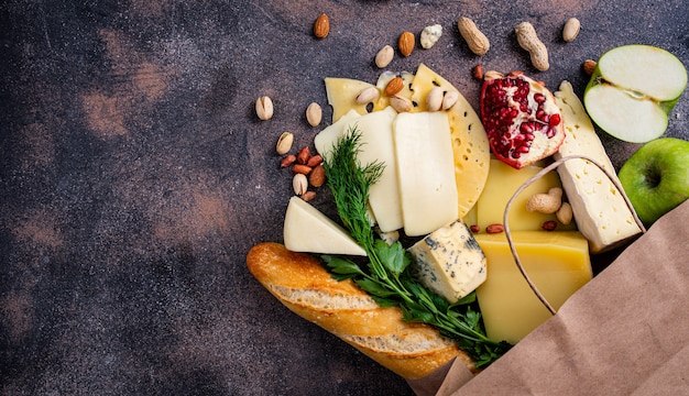 Sac en papier fromage et fruits et noix sur une table sombre