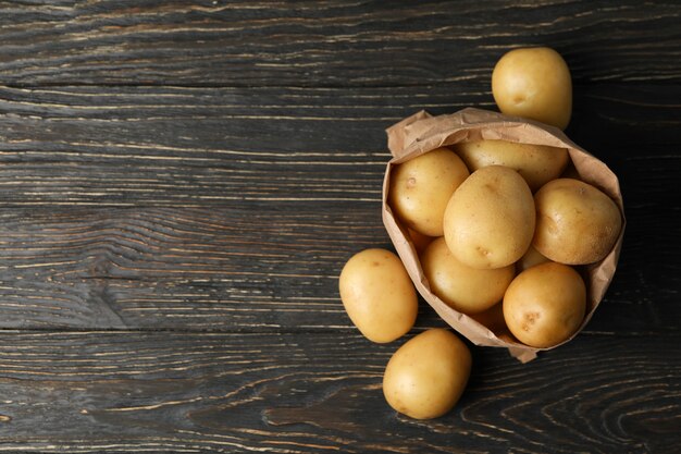 Sac en papier avec de jeunes pommes de terre sur une surface en bois