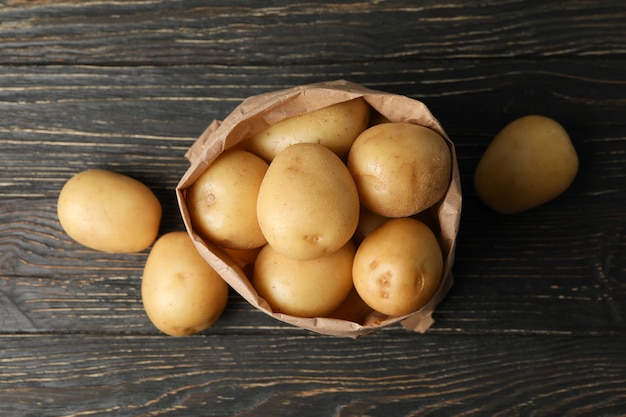 Sac en papier avec de jeunes pommes de terre sur une surface en bois