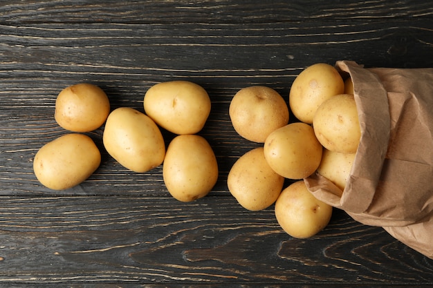 Sac en papier avec de jeunes pommes de terre sur une surface en bois