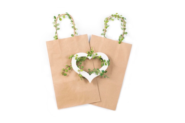 Sac en papier kraft et coeur en bois blanc tapissé enlacé de plante