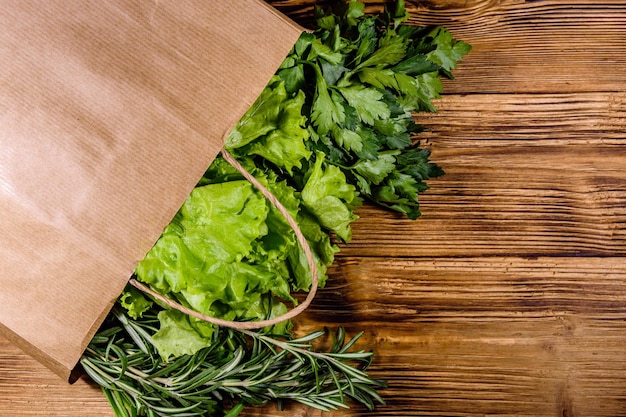 Sac en papier avec laitue romarin et persil sur une table en bois Nourriture végétalienne Vue de dessus