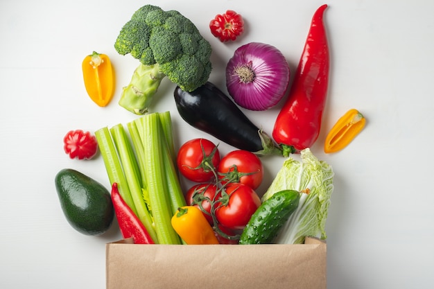 Sac en papier avec des légumes sur fond blanc.