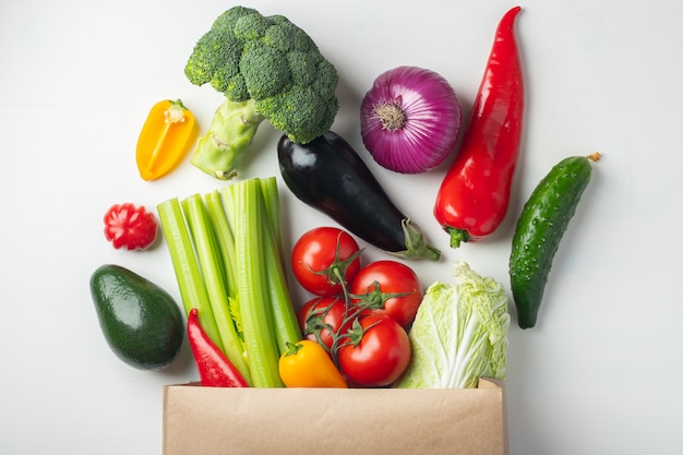 Sac en papier avec des légumes sur fond blanc.