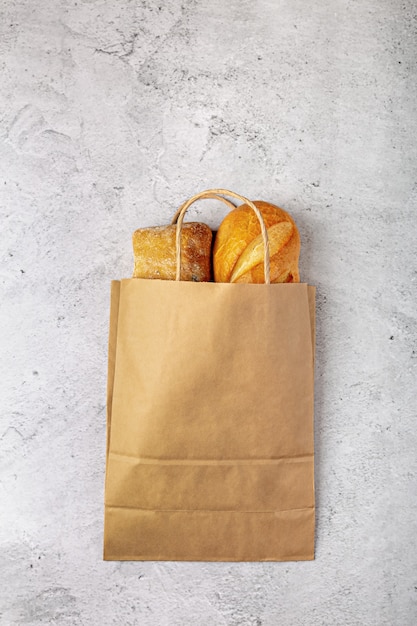 Sac en papier de supermarché recyclable avec des pains de pain cuits au four à plat sur fond gris avec copie espace