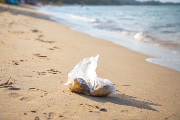Sac en plastique allongé sur une plage de sable tropical pollution environnementale poubelle dans la mer