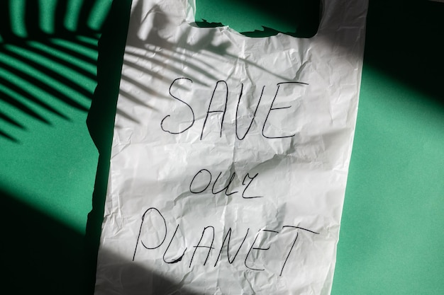 Le sac en plastique et l'inscription sauvent notre planète sur un fond vert