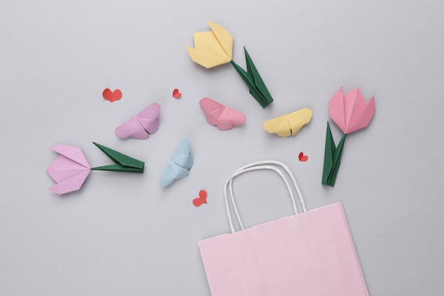 Sac à provisions et coeurs tulipes papillons sur fond gris vacances shopping réductions vente composition de la saint-valentin