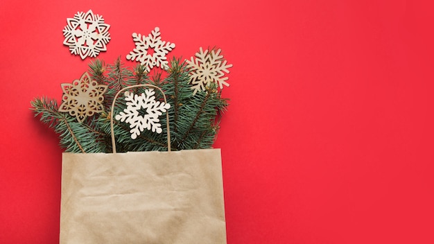 Sac à provisions avec décor de flocons de neige bricolage sculpté en bois de Noël et branches de sapin sur espace rouge