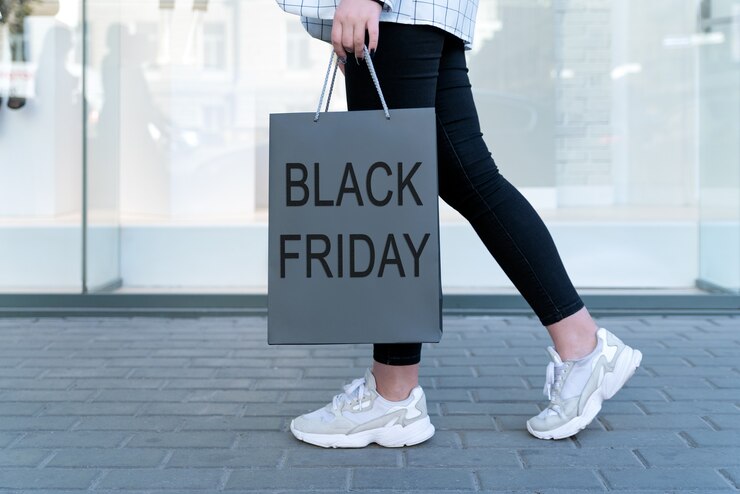 Photo sac à provisions avec inscription black friday sur l'espace des jambes féminines. concept commercial économique.