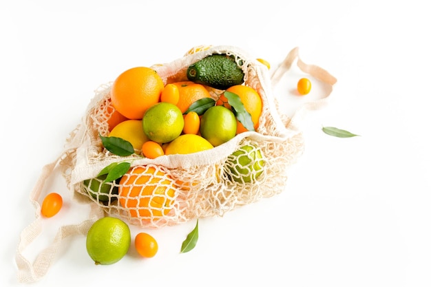 Sac à provisions en maille avec fruits tropicaux d'été orange citron citron vert sur fond blanc concept alimentaire plat vue de dessus concept d'été