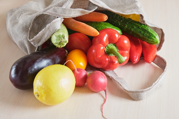 Sac à provisions tricoté en maille filet réutilisable écologique avec fruits et légumes sur la table, concept zéro déchet